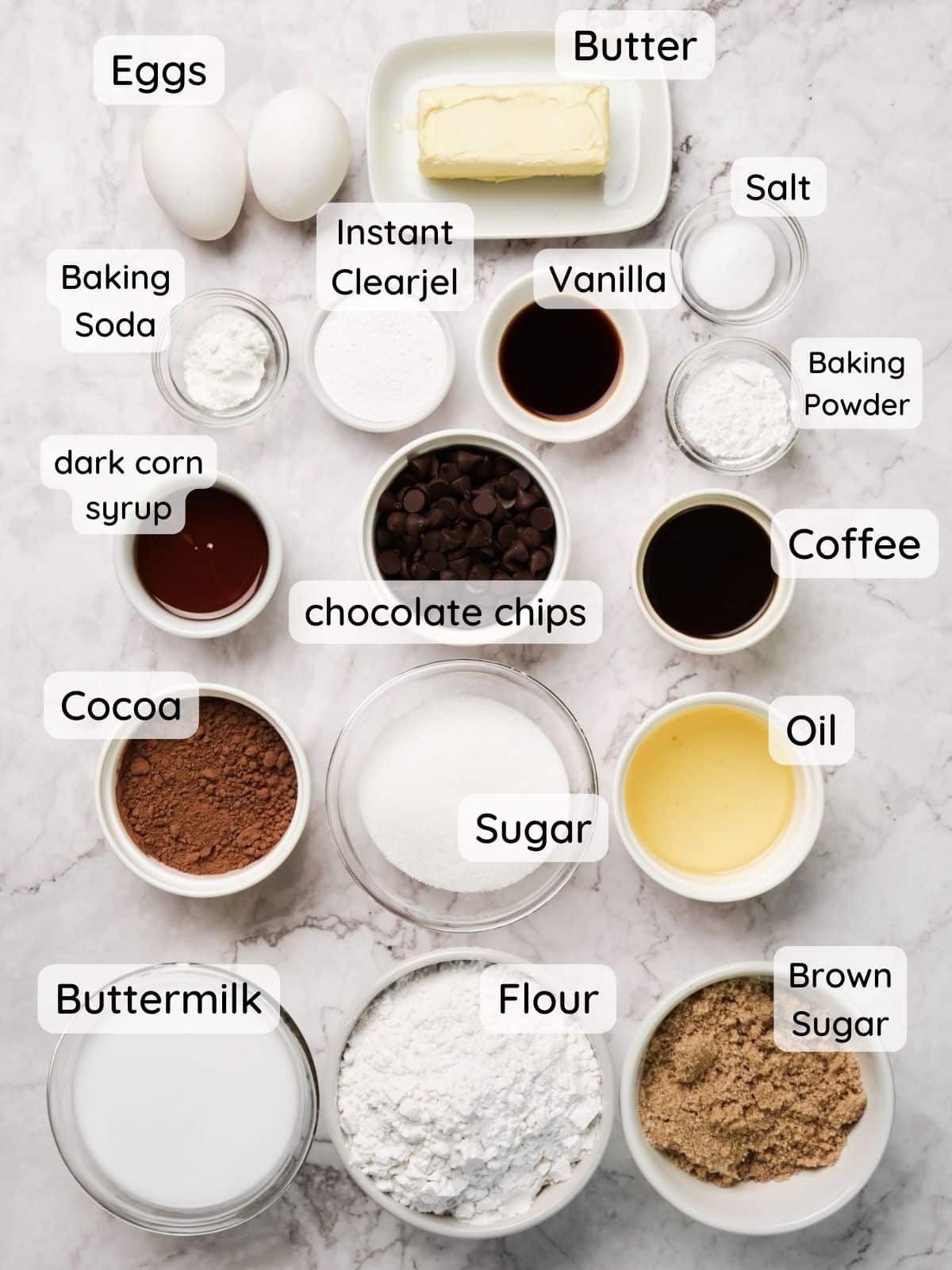 All the chocolate cake batter ingredients with the text: eggs, buttermilk, coffee, vanilla, dark corn syrup, flour, cocoa, baking powder, baking soda, instant clearjel, salt, sugar, brown sugar, chocolate chips."