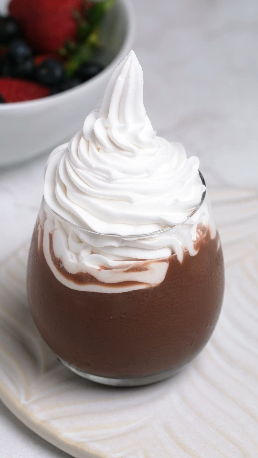 Tall thick and fluffy stabilized whipped cream in a cup.