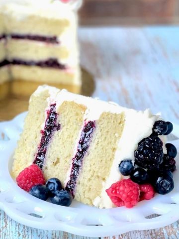 slice of vanilla cake made with the reverse creaming method with berry filling and a bowl of mixed berry cake filling