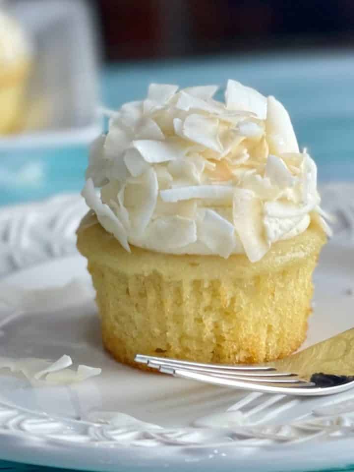 A plate with a Coconut Cream Cupcake with Whipped Cream Frosting