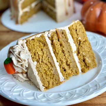 a closeup of a slice of three layer pumpkin spice cake that is visibly very moist
