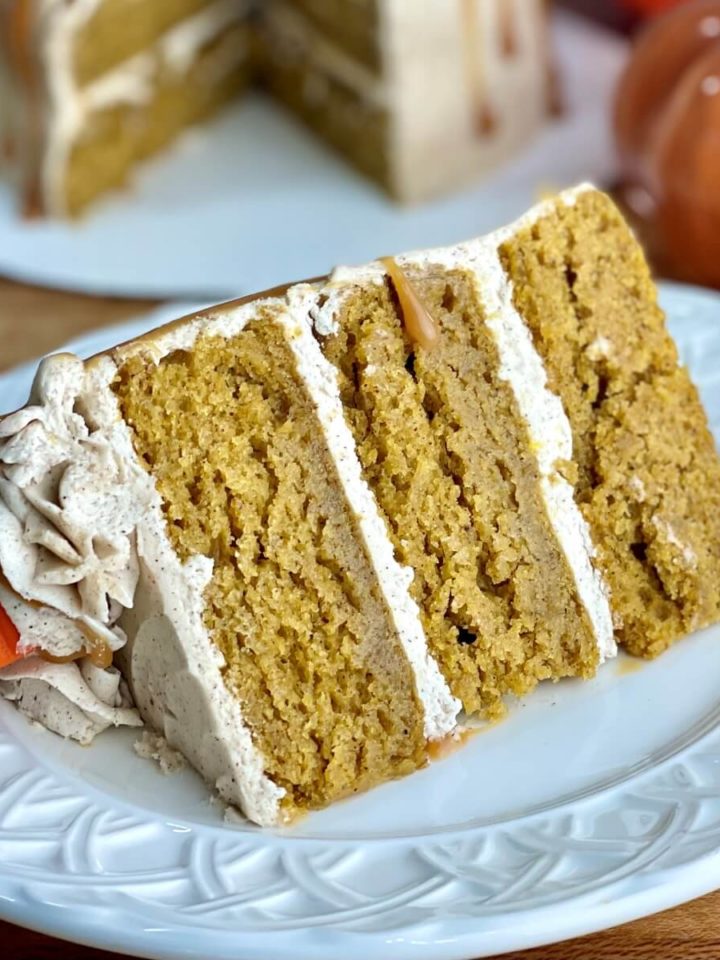 a closeup of a slice of three layer pumpkin spice cake that is visibly very moist