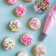 Several mini sugar cookies with a swirl of buttercream frosting and sprinkles