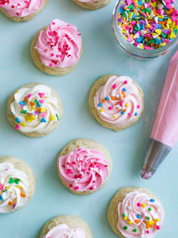 Several mini sugar cookies with a swirl of buttercream frosting and sprinkles