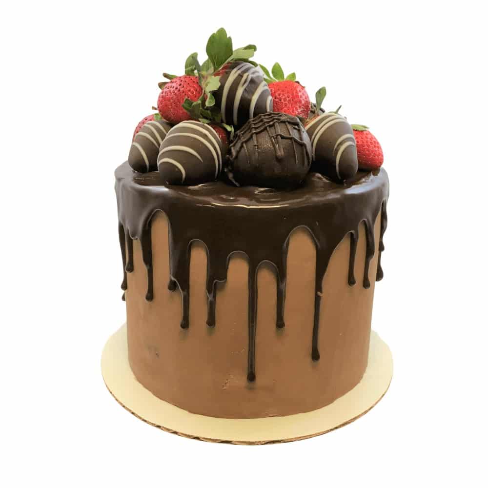 A chocolate cake with a chocolate ganache drizzle and chocolate covered strawberries on top