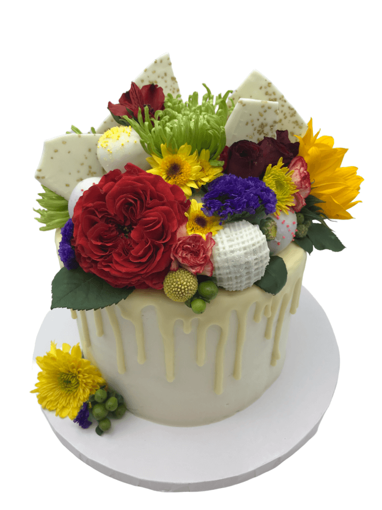 a white cake with white chocolate ganache drizzle and fresh flowers on top