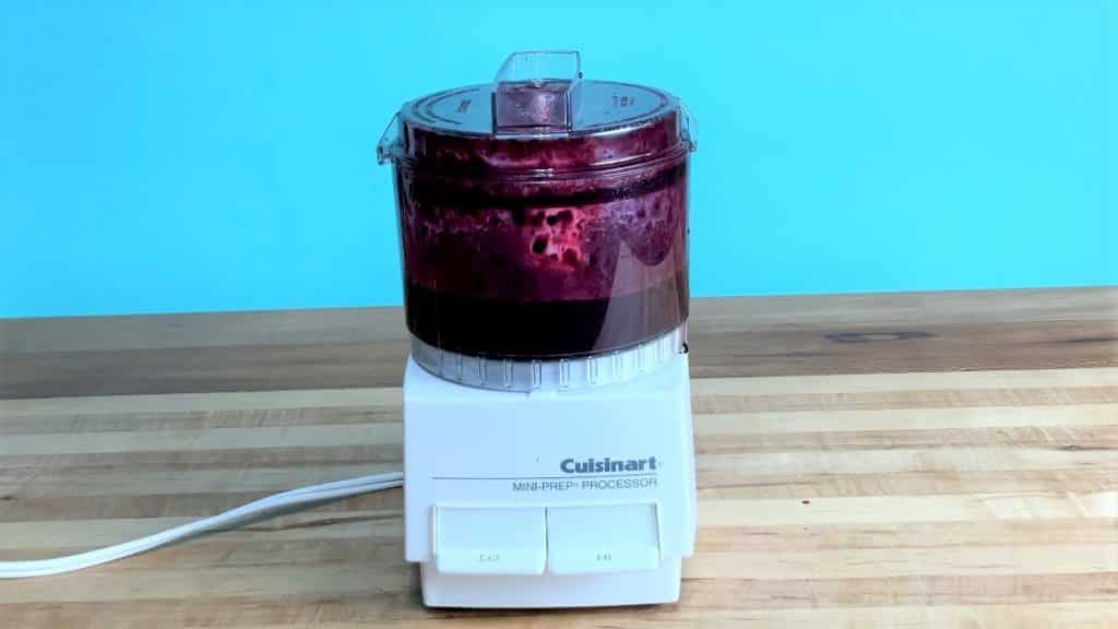 A small food processor containing blueberry puree.