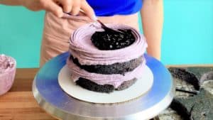 A blueberry layer cake being filled with blueberry compote filling.