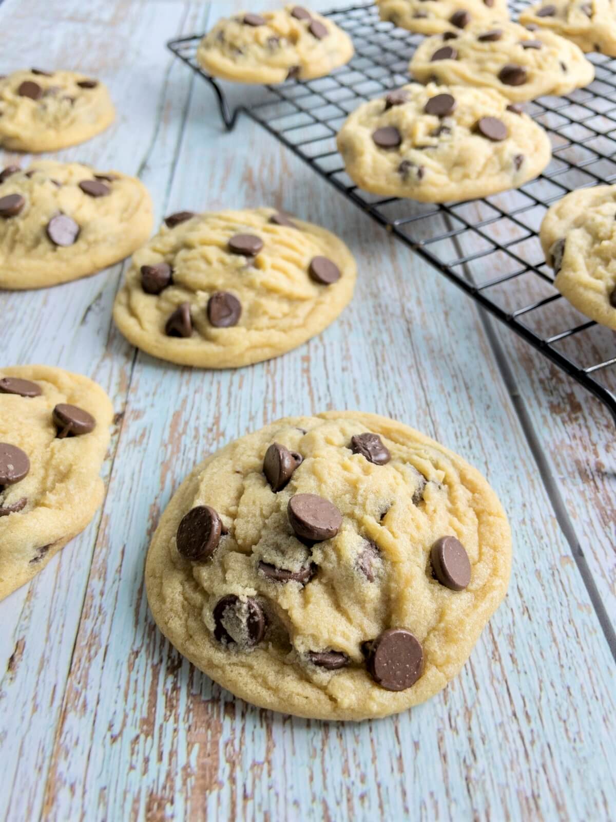 several bakery style chocolate chip cookies on a table and cooling rack