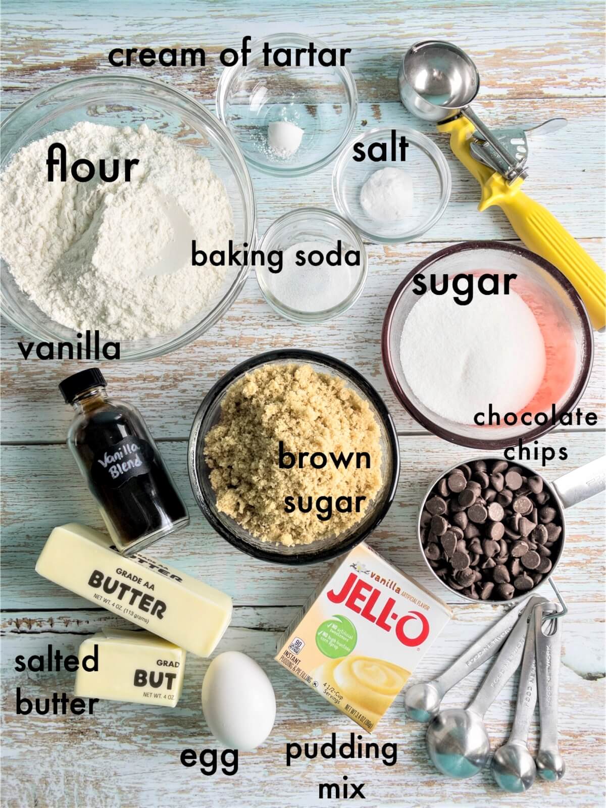 An overhead shot of the Ingredients to make chewy chocolate chip cookies with the following text overlays: flour, baking soda, salt, cream of tartar, sugar, brown sugar, salted butter, instant pudding mix, vanilla, chocolate chips