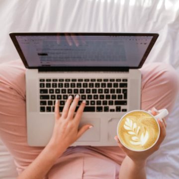 a woman working on a laptop with a coffee