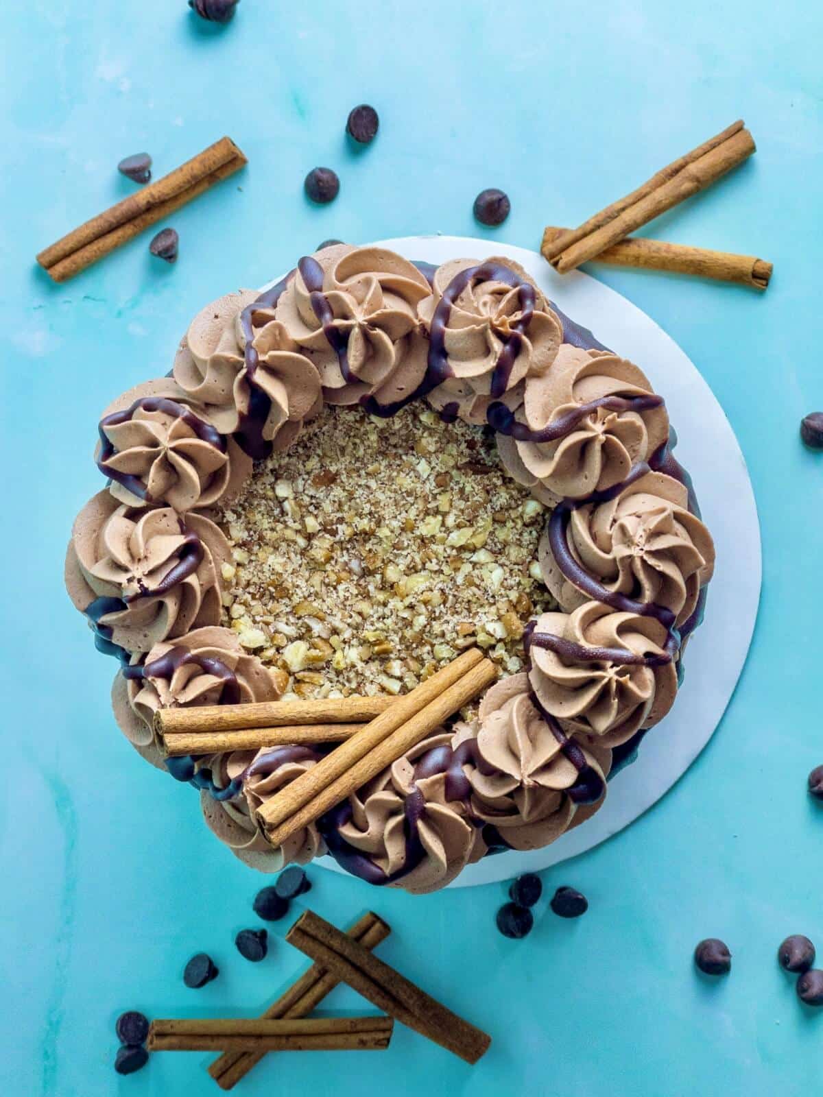an overhead shot of chocolate cinnamon cake with pecans on top of the cake and cinnamon sticks