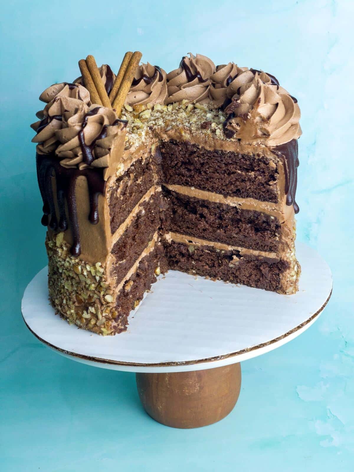 a chocolate cinnamon layer cake on a cake stand with several slices missing