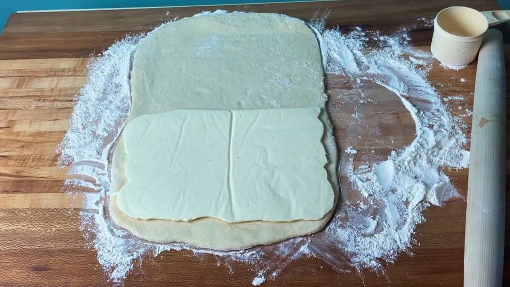 A rectangle of rolled out pastry dough with a smaller rectangle of firm butter filling on top