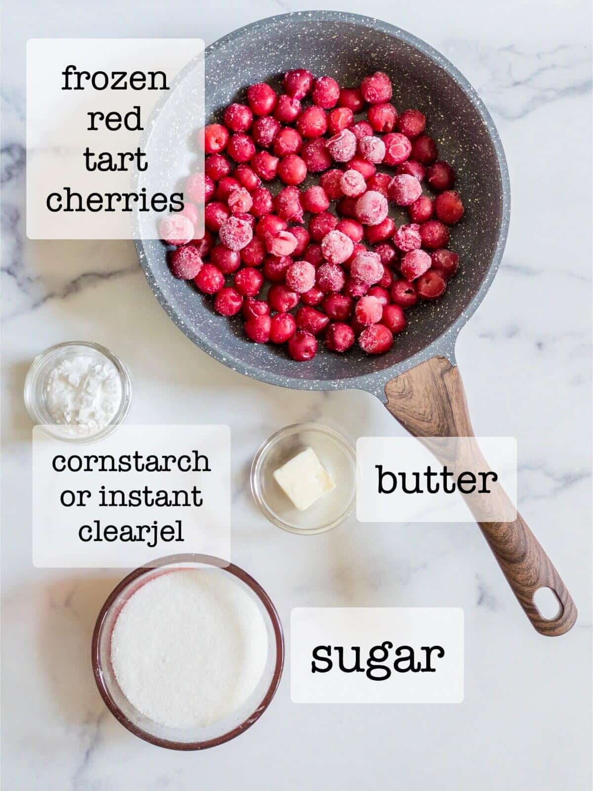 An overhead shot of cherry filling ingredients-frozen tart red cherries, sugar, instant clearjel or cornstarch, and butter