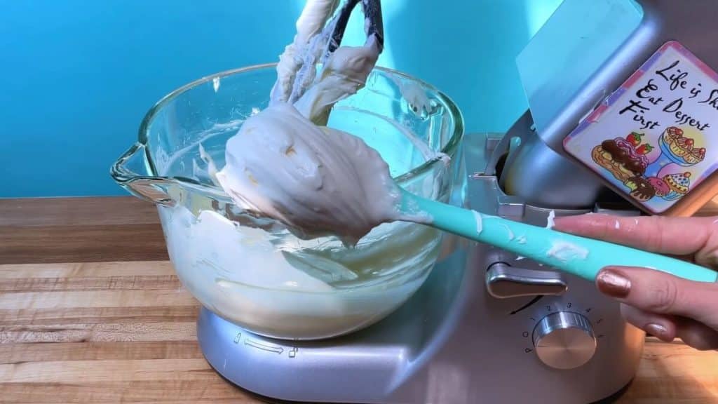 A mixing bowl with cream cheese filling and a spatula showing the creamy consistency.
