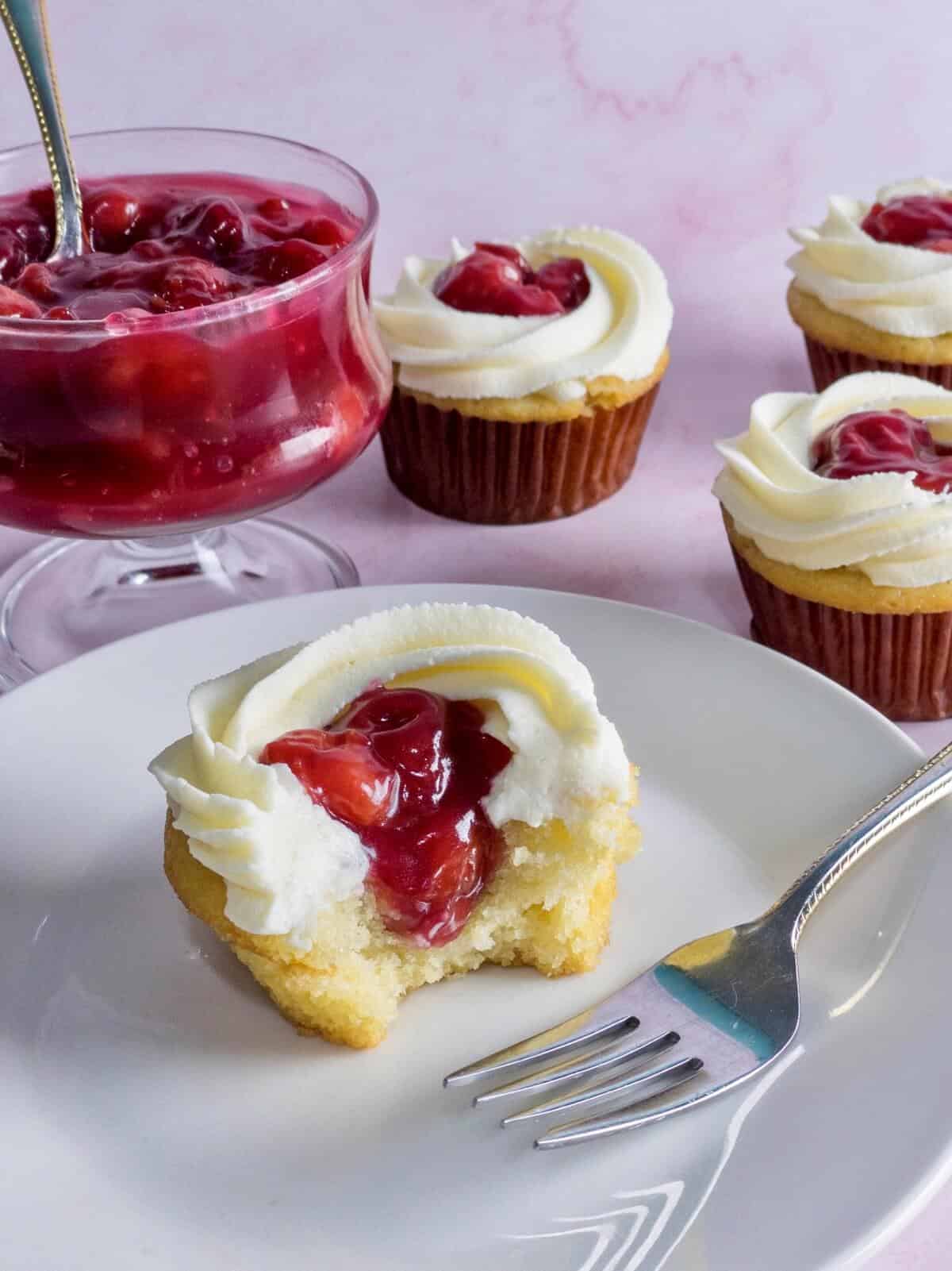 A closeup of a vanilla cupcake filled with cherry pie filling from scratch