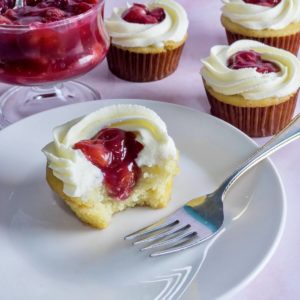 A closeup of a vanilla cupcake filled with cherry filling
