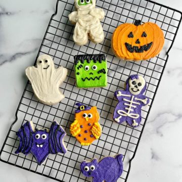 Several Halloween buttercream decorated sugar cookies on a cooling rack