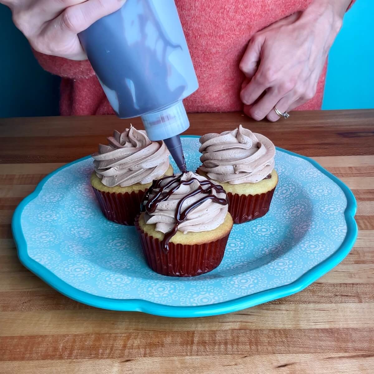 Nutella cupcakes being drizzled with chocolate ganache.