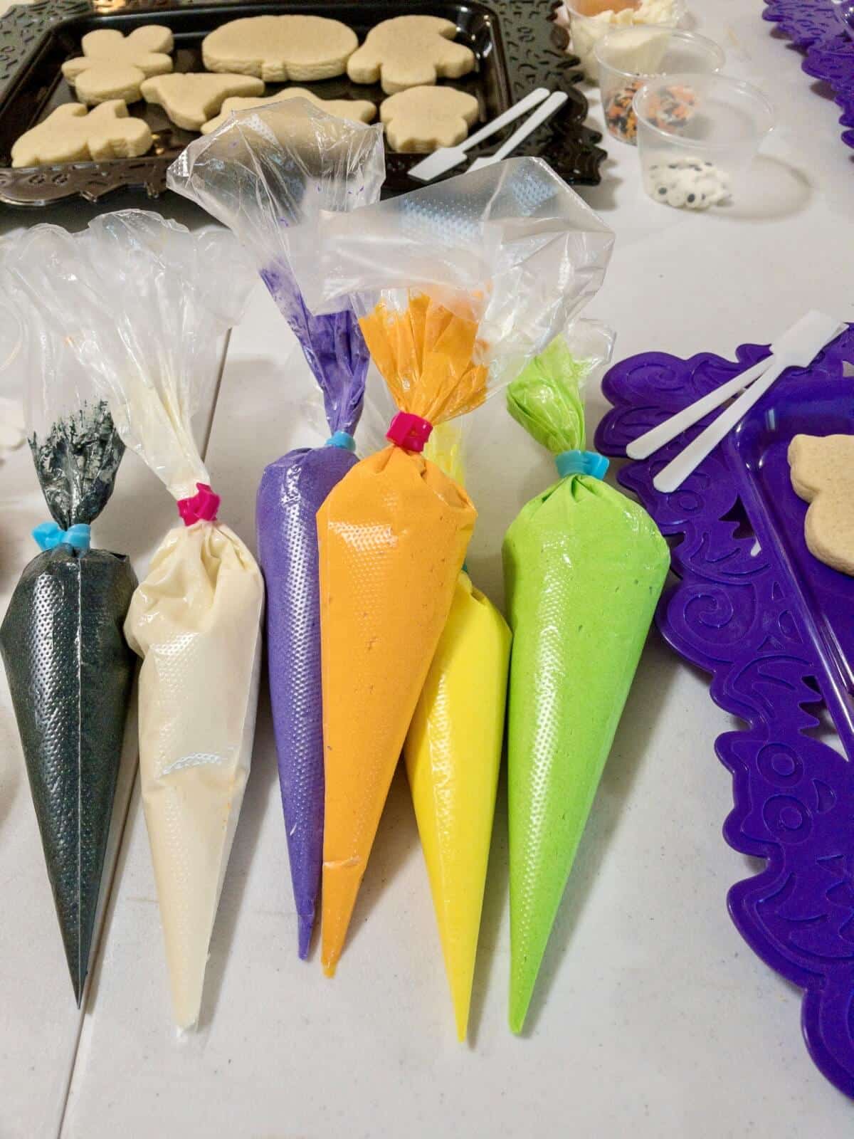 Several disposable piping bags filled with colorful buttercream frosting