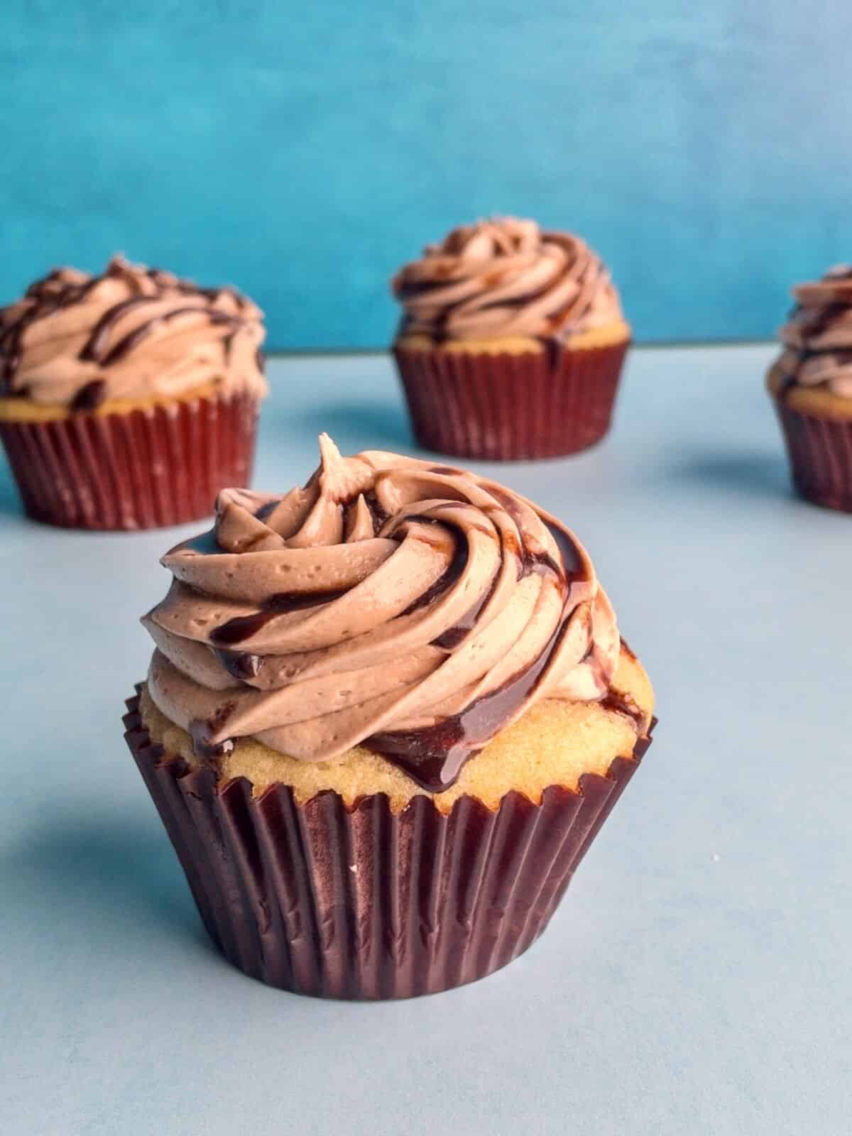 A closeup of a yellow cupcake with a chocolate drizzle