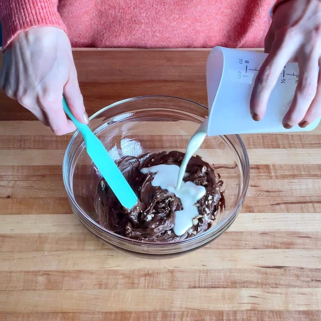 Nutella being mixed with heavy cream and chopped hazelnuts