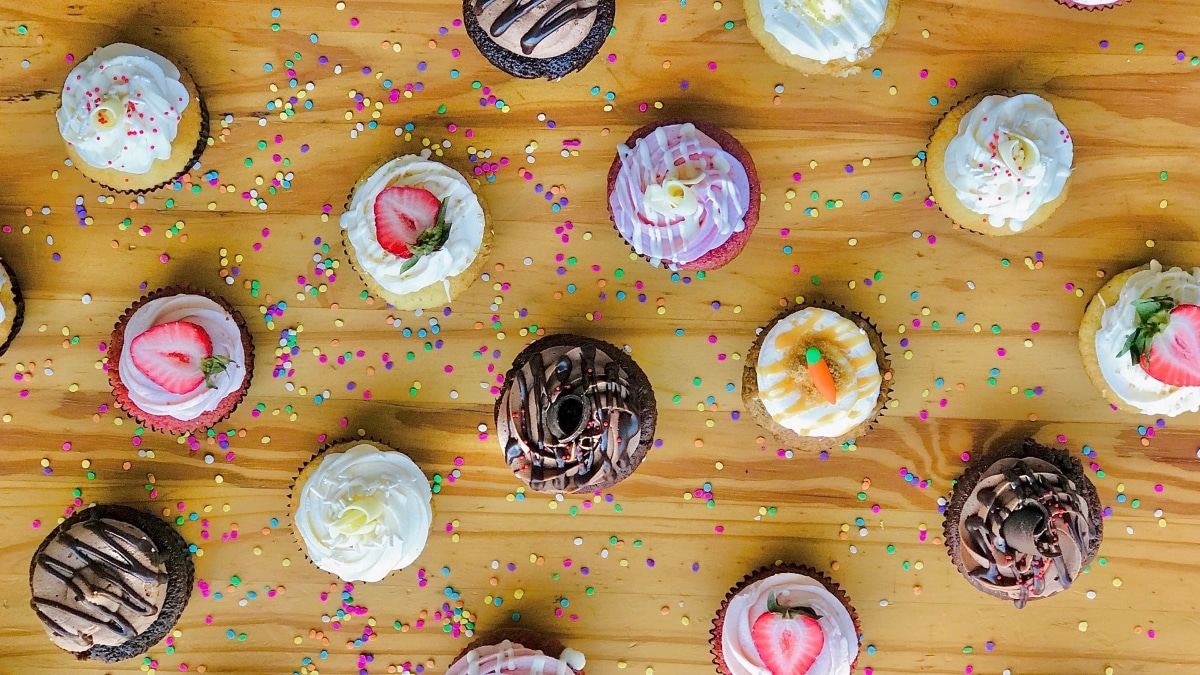 An overhead shot of decorated bakery-style cupcakes on a table