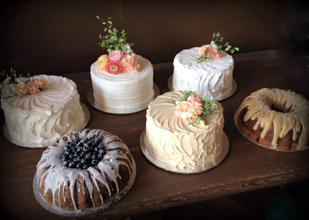 A table with a variety of 6 bakery cakes, all decorated differently.