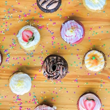a variety of homemade cupcakes on a wooden table.