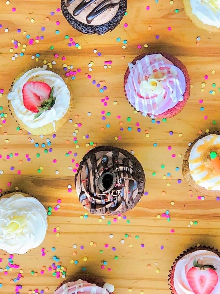 a variety of homemade cupcakes on a wooden table.