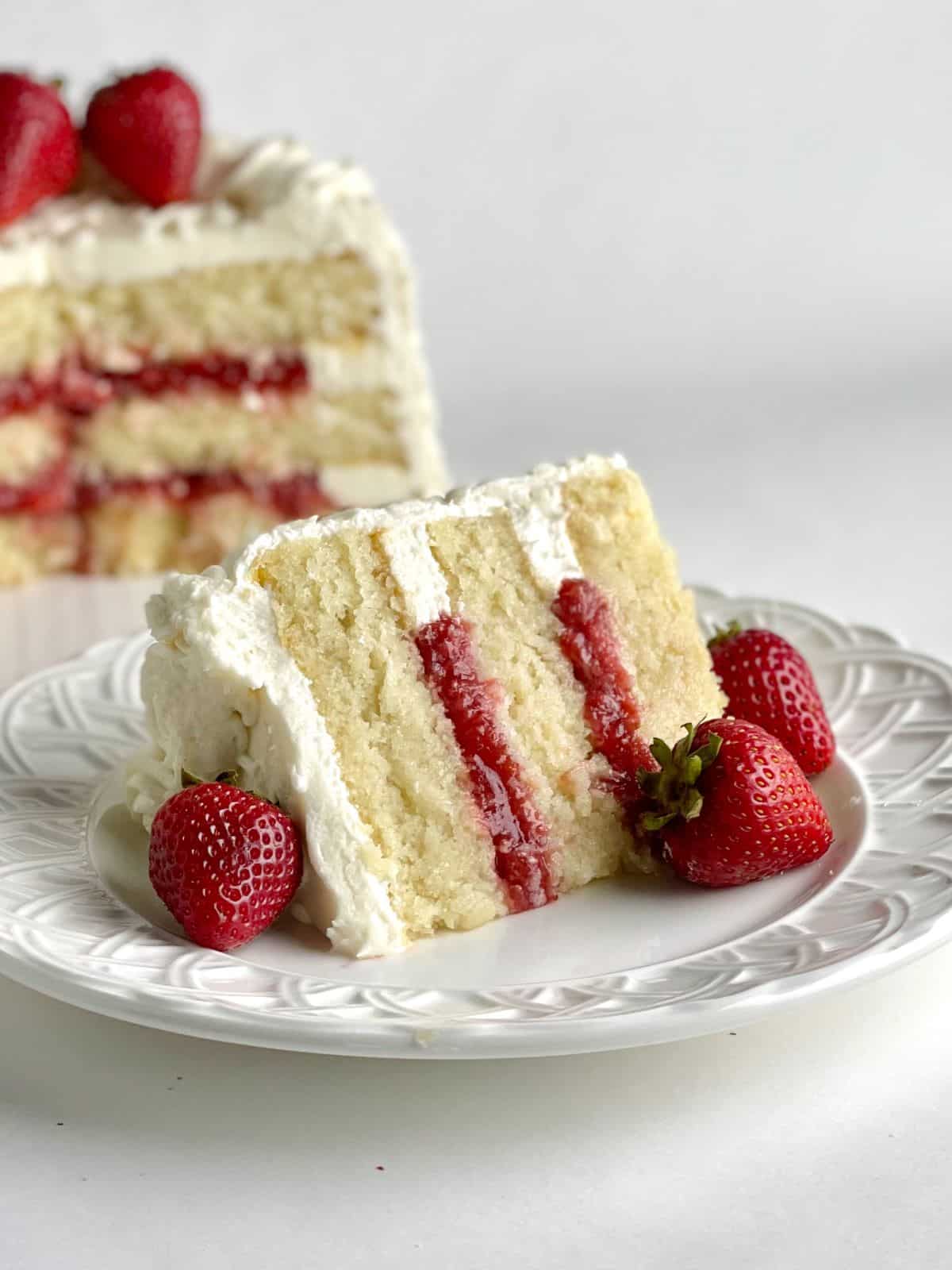 A slice of cake with Strawberry Cake Filling flavor and the rest of the cake in the background.