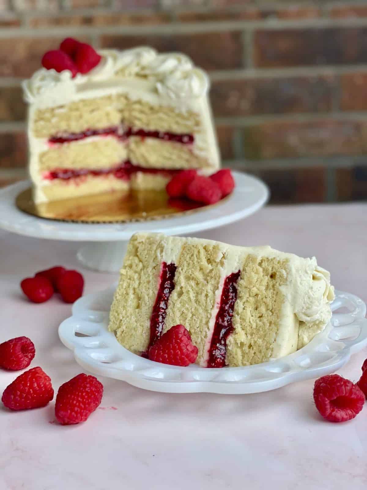 A layered cake with Raspberry Cake Filling with the remaining cake on a cake pedistal.