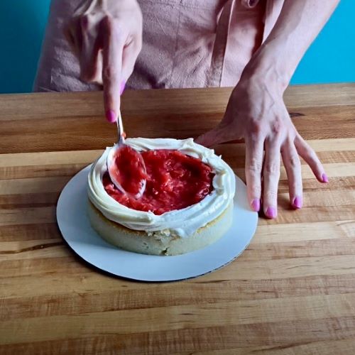 A layer of cake with a ring of buttercream containing strawberry cake filling.