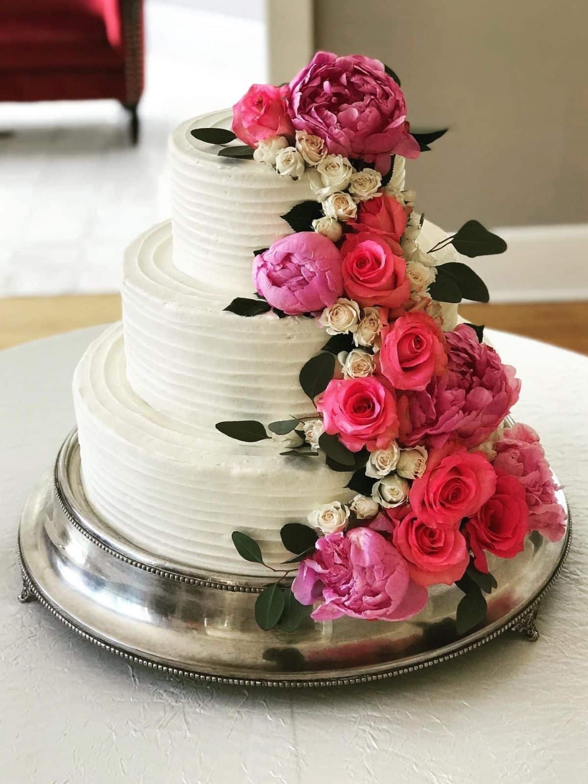 A tiered wedding cake on a cake stand at a wedding venue.