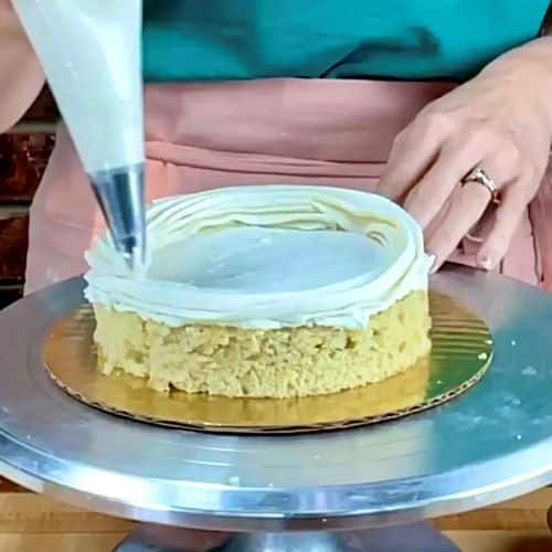 A cake layer being prepared for cake filling with a ring of buttercream to contain the cake fillings.
