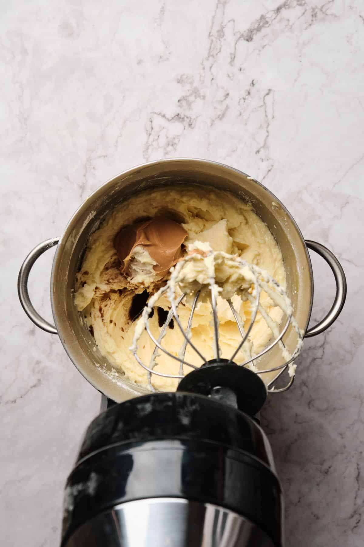 Peanut butter buttercream being blended in a mixer.