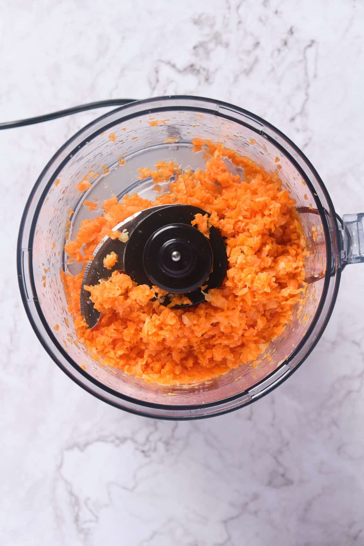 mini carrots and crushed pineapple being processed in a food processor.