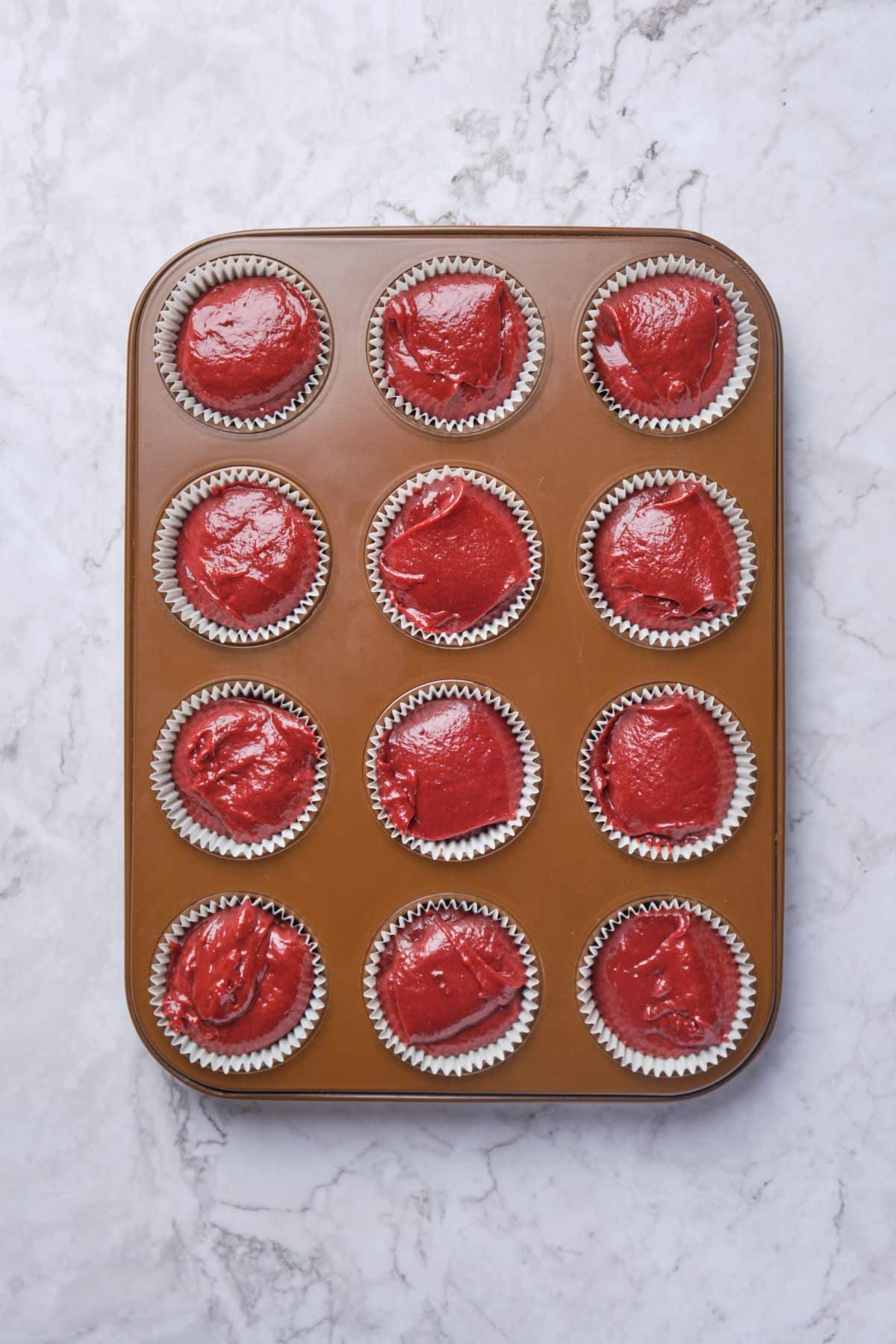 Red velvet cupcakes batter in a cupcake tin.