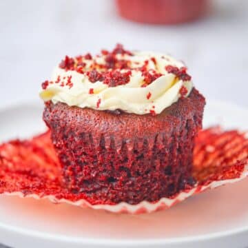 A moist red velvet cupcake with the wrapper off showing its moist texture.
