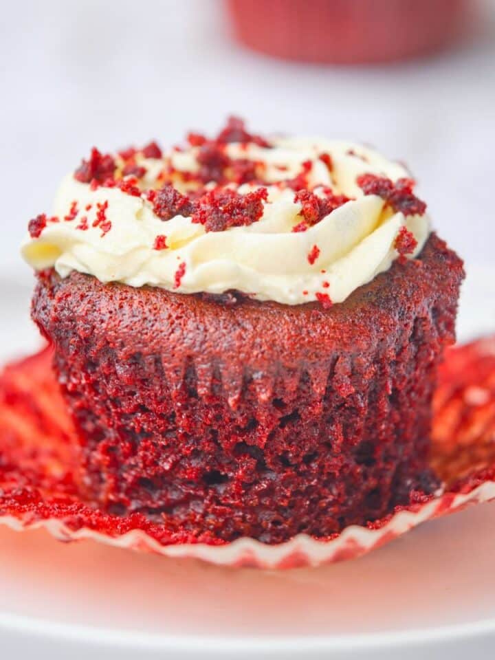 A moist red velvet cupcake with the wrapper off showing its moist texture.