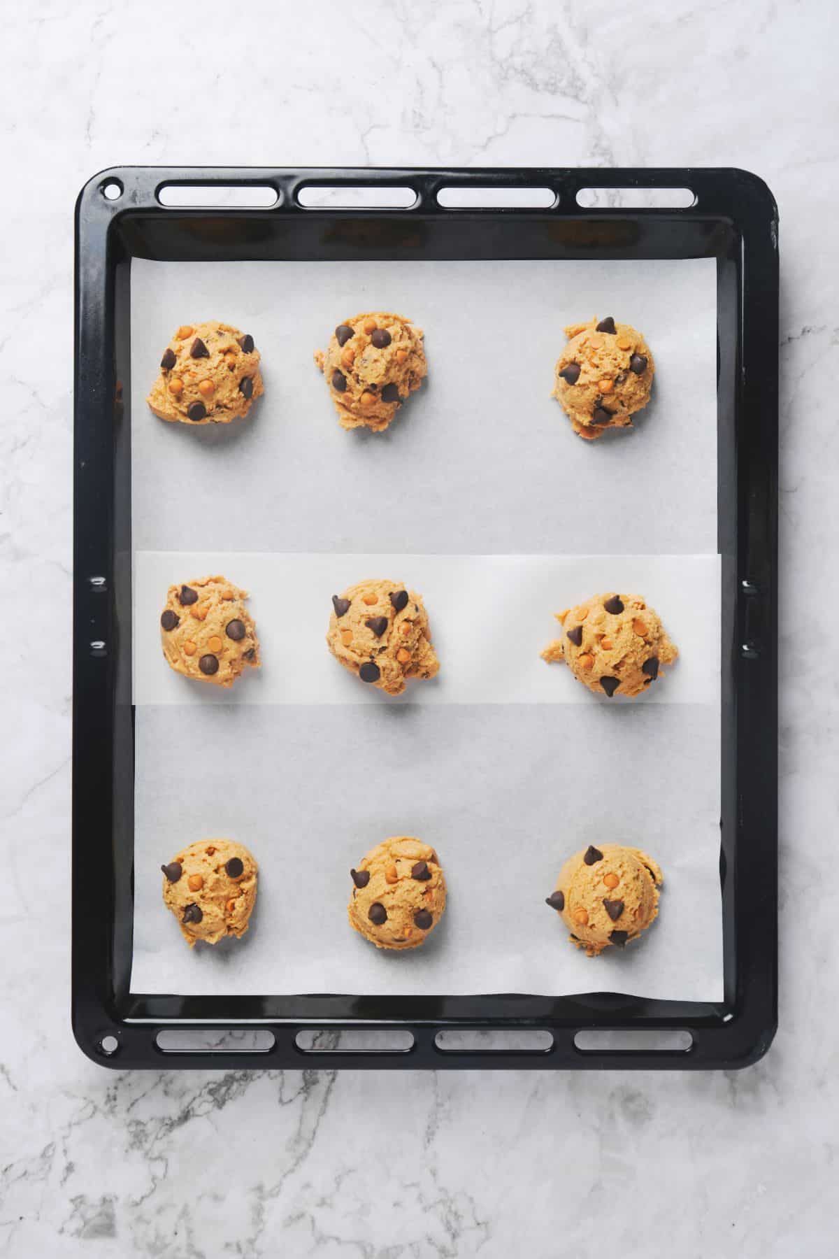 Chocolate chip butterscotch cookie balls on a cookie tray.