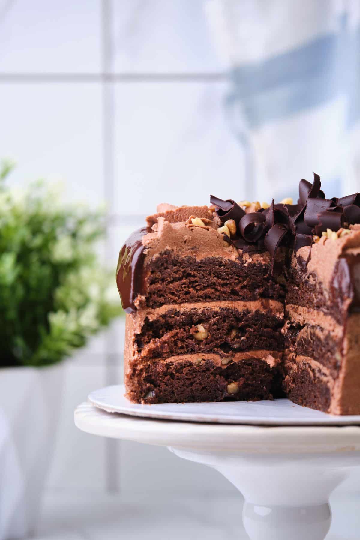 A chocolate walnut layer cake with several slices taken out.