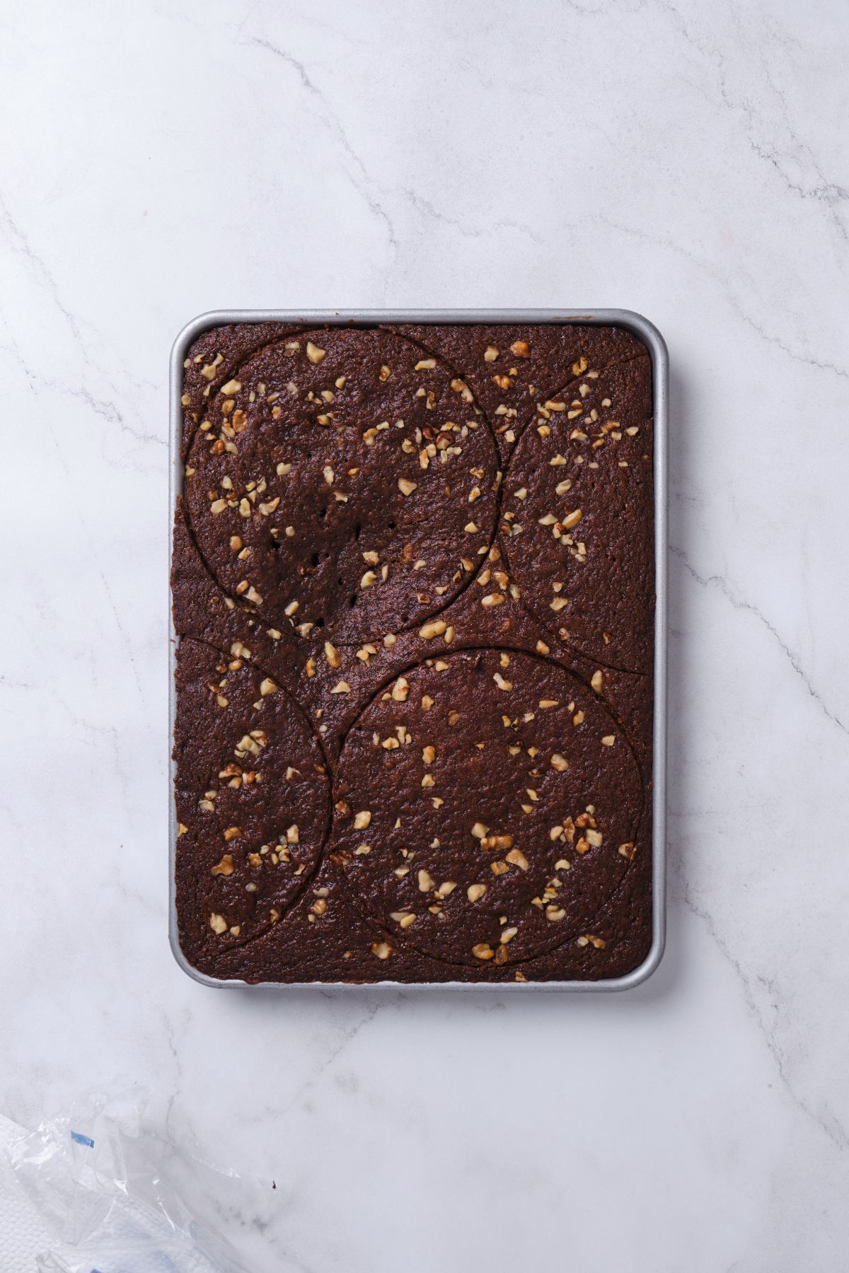 Chocolate walnut cake in a sheet pan cut out with cake rings.