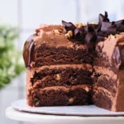 A three layer chocolate walnut cake cut open to show the moist layers.