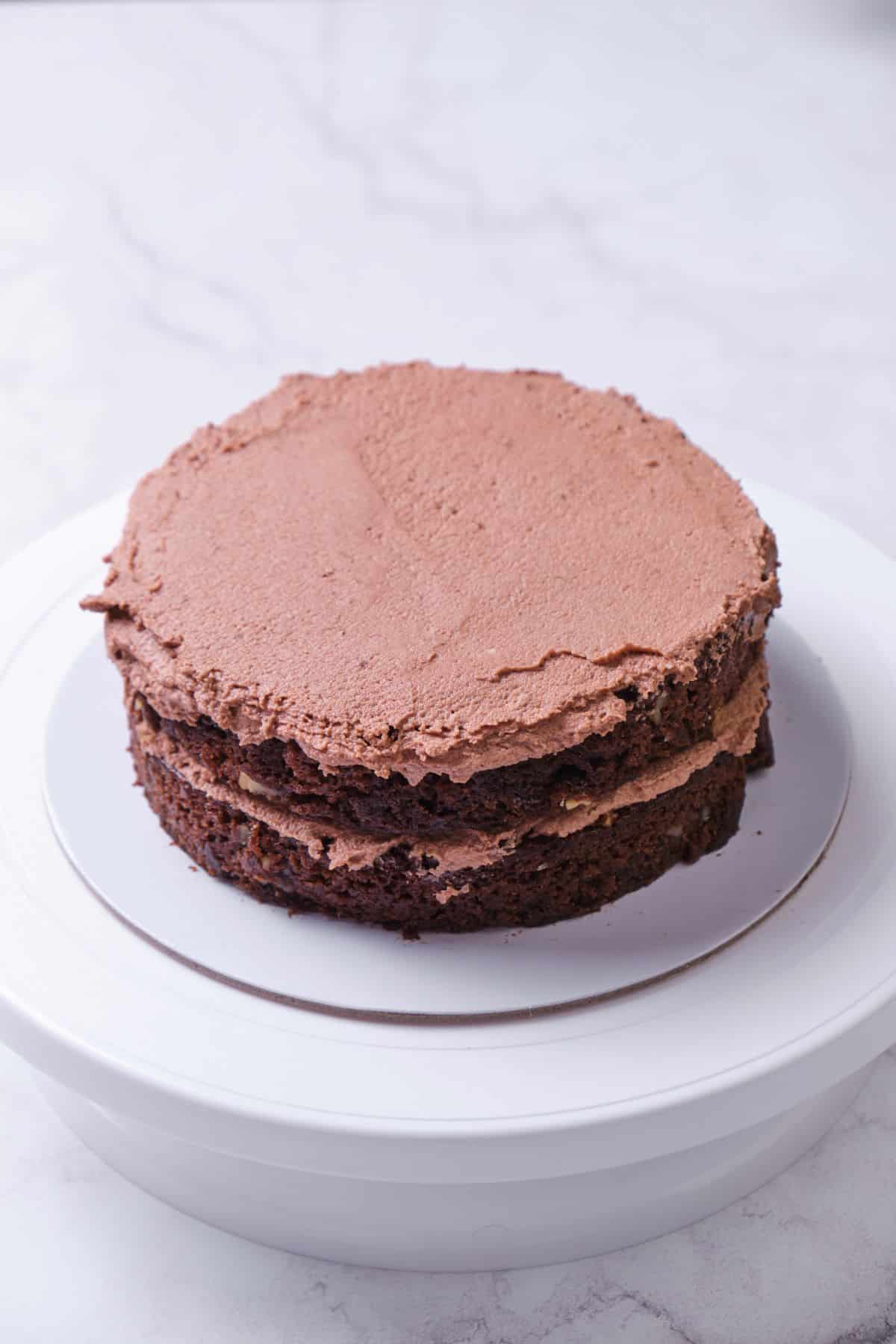 Two layers of a chocolate cake being layered.