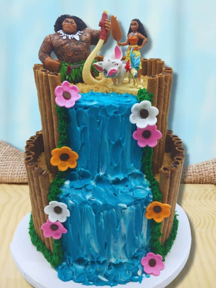 A two tiered Moana Cake with a buttercream waterfall and Moana Cake toppers.