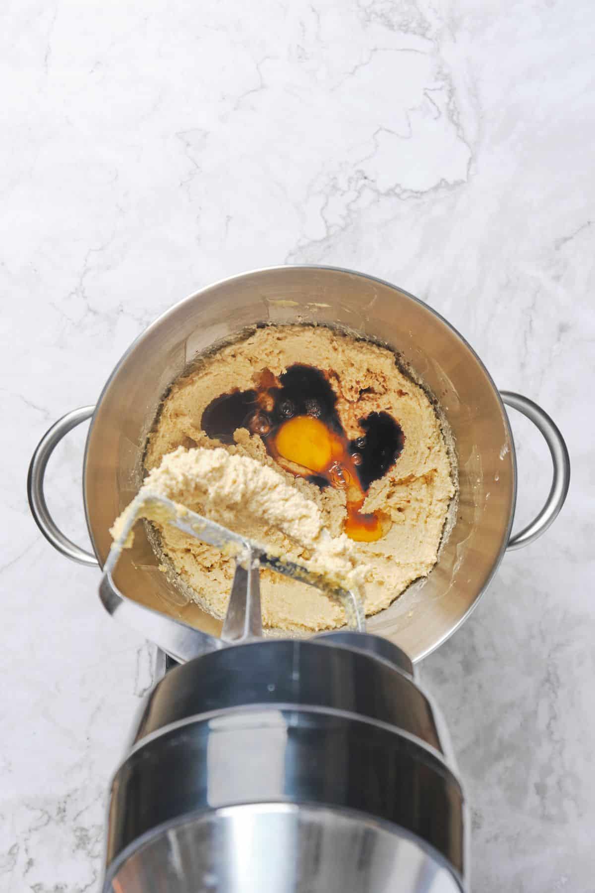 Egg and vanilla added to a stand mixer bowl of creamed butter, brown sugar, and white sugar.