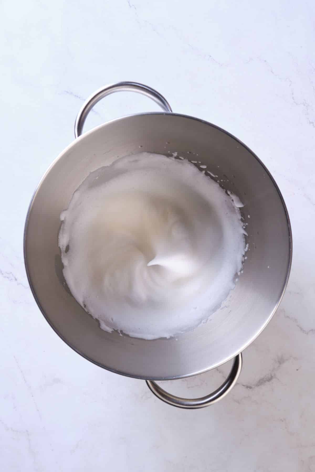 Beaten Egg whites in a stand mixer bowl.