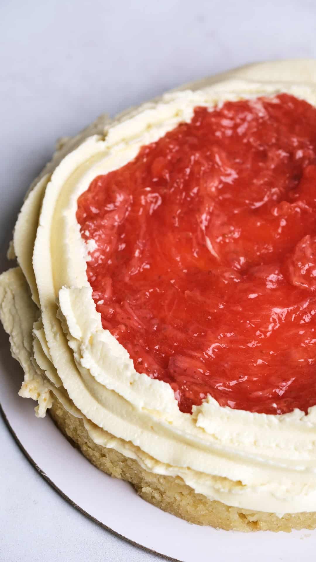 A layer cake being filled with strawberry filling.